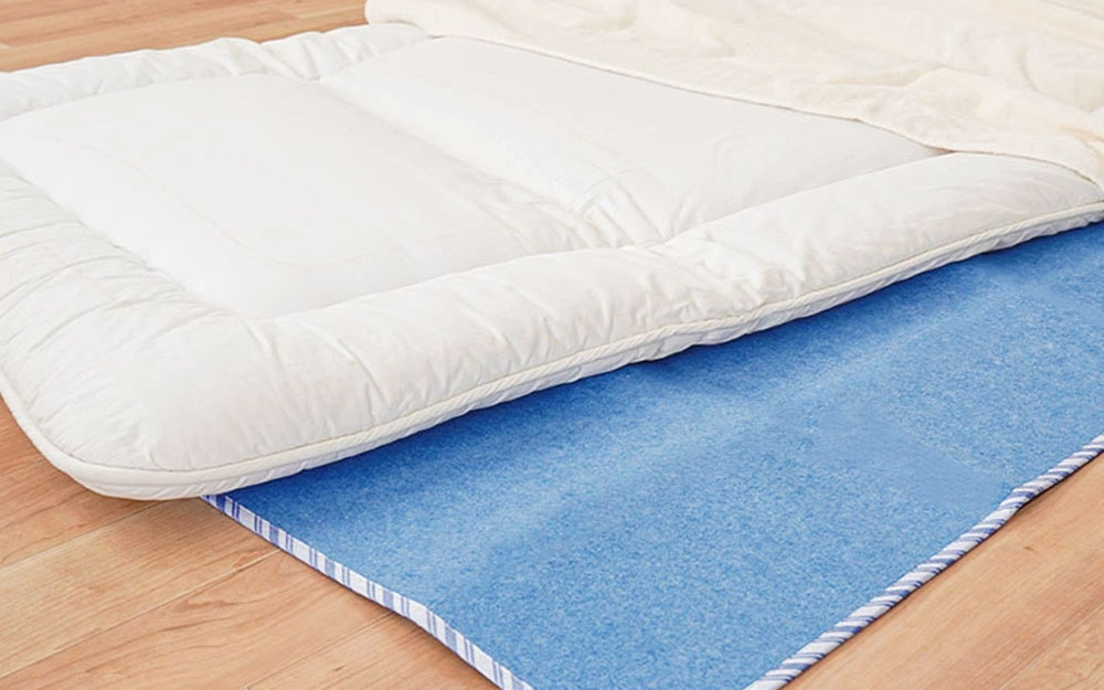 マットレスの下に敷いた除湿シートや敷きパッドの状態を確認している様子